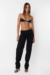 Pantalón negro de tiro medio con terminación de tela en cintura y ruedo al corte para que desfleque. Detalle de falsa cintura aplicada en todo el contorno de cartera, con presillas y cinto tira incluido. En trasero, bolsillos ribete sastrero.