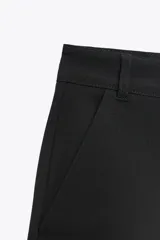 Shorts tiro bajo color negro con bolsillos delanteros. Cierre frontal con cremallera y ganchos metálicos.