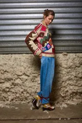Sweater de lana color crema con cuello redondo, mangas largas y diseño tejido con motivos geométricos y florales en tonos marrones, rojos, verdes, azules y rosas.