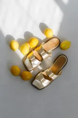 Sandalias doradas con tiras entrelazadas y suela plana.