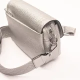 Bandolera plateada con textura granulada, correa ancha de tela con diseño geométrico y cierre con broche imantado.