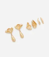 Kit de tres pares de caravanas de metal con acabado dorado y superficie irregular texturizada. El conjunto incluye un par con diseño de flor y dije colgante, un par con forma de hoja y un par pequeño con forma de pétalo.