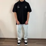 Chomba azul de piqué con cuello clásico y manga corta. Presenta bordados blancos con motivos de golf en el pecho.