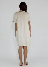 Vestido corto color beige de lino y algodón, con escote en V y mangas cortas.