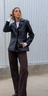 Blazer azul marino gastado de cuero ovino, con solapas de muesca, cierre frontal con botones, bolsillo de parche en el pecho y bolsillos con solapa en la parte inferior.