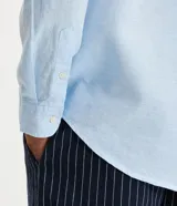 Camisa celeste de lino con cuello camisero, abotonadura frontal y mangas largas.