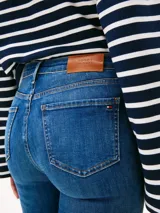 Jean de mujer de tejido denim rígido, color azul medio con efecto desteñido en muslos y rodillas. Presenta un corte de pierna ancha y talle alto, con cierre de cremallera y botón, y estilo de cinco bolsillos.