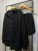Conjunto de camisa de manga larga con botones y short, ambos de tela arrugada color negro.