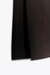 Pantalón marrón de vestir, de tiro medio y corte recto. Presenta bolsillos delanteros, cierre frontal con cremallera y gancho metálico.