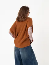 Poncho de tejido grueso color beige, con cuello alto y mangas cortas.