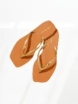 Chinelas color tostado con tiras finas doradas y logo de la marca Agua de Coco en la plantilla.
