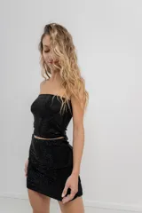 Minifalda negra ajustada al cuerpo, confeccionada en tejido elástico con strass plateado.