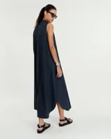 Vestido evasé sin mangas confeccionado en denim liviano, con cuello mao y falsa cartera que forma un escote en V con tabla central delantera. Posee bolsillos laterales, tablón en el centro de la espalda y ruedo redondeado con tajos laterales. Largo hasta mitad de la pantorrilla.