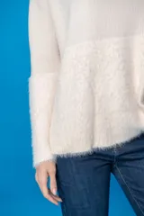 Sweater color crudo con cuello alto, mangas largas y diseño de punto con textura peluda en la parte inferior.