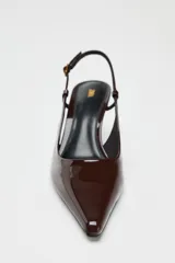 Zapato de tacón destalonado color marrón charol, con punta fina y tira trasera con hebilla.