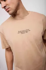 Remera beige con estampado de texto en el pecho.
