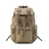 Mochila de tela canvas color verde oliva con tapa y detalles en símil cuero marrón. Cierre superior marinero, bolsillos internos, externos frontal, laterales y trasero con cierre. Asas rígidas, correas ajustables y espacio para laptop de 15".