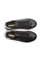 Zapatillas bajas negras de cuero liso, con cordones y suela blanca.