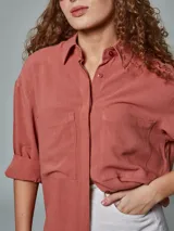 Camisa oversize color ladrillo confeccionada en lino, con cuello clásico, manga corta y bolsillo en el pecho.