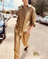 Pantalón de lino metalizado color dorado, de corte recto, con bolsillos laterales y traseros, y elástico en la cintura.