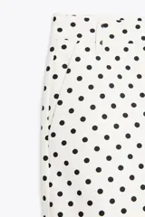 Shorts blancos con lunares negros, de tiro medio con trabillas, bolsillos laterales y falsos bolsillos de vivo en la espalda.