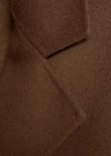 Abrigo marrón de lana con doble botonadura, cuello con solapa de muesca, dos bolsillos laterales, hombros caídos, diseño oversize y largo, con forro interior.