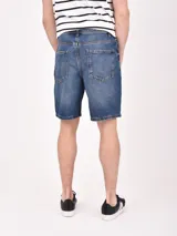 Bermuda de jean negro con roturas y corte a la rodilla.