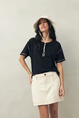 Remera blanca de algodón liviano, de manga corta y cuello redondo. Presenta costuras a contratono visibles en hombros y mangas.