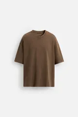 Camiseta marrón de algodón, corte holgado, cuello redondo y mangas cortas. Tiene un efecto lavado que le da una apariencia única.