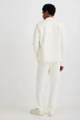 Pantalón jogger color crudo, de corte slim fit, confeccionado en sarga. Presenta cintura elástica con cordón ajustable, bolsillos laterales al bies y bolsillos traseros insertados.