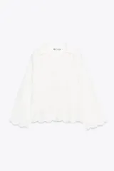 Blusa blanca de algodón con cuello solapa, escote pico y manga larga acampanada. Detalle de frunces y bordados a tono.