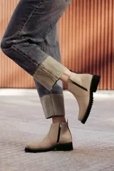 Bota de cuero color beige con cierre lateral metálico y taco medio.