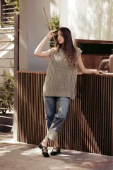 Chaleco de punto color crema con cuello alto y diseño de trenzas.