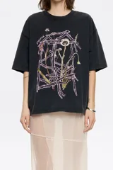 Remera negra de algodón con cuello redondo y manga corta. Estampado frontal con diseño floral abstracto en tonos rosa y marrón.