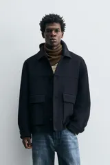 Abrigo relaxed fit confeccionado en tejido con mezcla de lana. Cuello solapa y manga larga acabada en puño con botón. Bolsillos con solapa en cadera. Cierre frontal de botonadura.