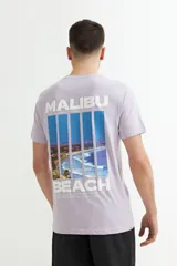 Remera de hombre color lavanda con estampado frontal que dice 'Malibu Beach'.