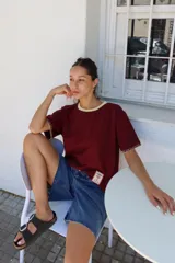 Remera de algodón color azul marino, corte relajado con hombro caído. Presenta cuello redondo blanco y bordado a mano en contraste en los puños de las mangas. Tiene un parche bordado en la parte inferior del frente.