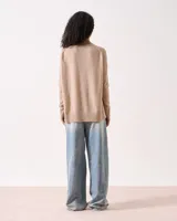 Sweater de tejido de punto color beige claro, con cuello redondo, manga larga y sisa caída. Presenta un detalle de costura vertical central en el frente y terminaciones acanaladas en puños y ruedo.