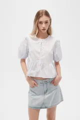 Blusa de algodón a rayas verticales color celeste y blanco, con cuello redondo, mangas cortas abullonadas y corte peplum.