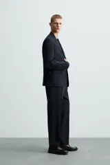 Pantalón de vestir azul marino, de corte recto, con bolsillos laterales y traseros. Se ajusta a la cintura con cinturón de cuero marrón.