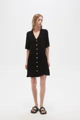 Vestido corto color crema, de corte holgado, con cuello en V y botones frontales.