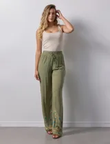 Pantalón verde oliva de rayón con cintura elastizada tipo smock y bordados florales en los bajos.