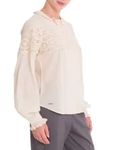 Blusa beige de algodón orgánico con cuello alto y detalles de broderie en la parte superior.