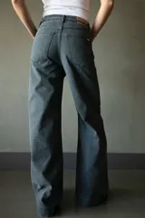 Pantalón de jean azul oscuro de pierna ancha con detalle de trenzado en bolsillos y cinturón.