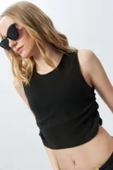 Cropped top negro sin mangas con frunces en los laterales y cuello a la base, con textil lavado.
