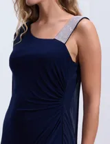Vestido de fiesta azul marino de seda fría, corte a la rodilla, con un hombro descubierto y aplique de lentejuelas plateadas en el bretel. Incluye una capa de gasa transparente que se sujeta al hombro.