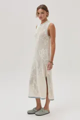 Vestido midi tejido de punto color crudo, con calados florales, calce recto, tajos laterales y detalles en celeste en cuello, sisas y ruedo.