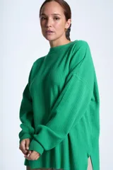 Sweater color beige de tejido de punto acanalado, con cuello redondo y mangas largas. Tiene corte holgado y aberturas laterales en el ruedo.