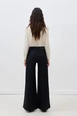 Pantalón de jean negro de tiro alto y pierna palazzo, confeccionado en denim con elastano y coating negro con apariencia similar al cuero.