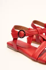 Sandalias franciscanas rojas de cuero con tiras entretejidas y hebilla lateral.